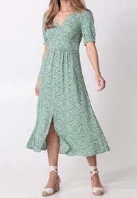 Green floral midi dress with short puff sleeves, V-neck, button details, and front slit. Made of lightweight fabric with a flowing design.