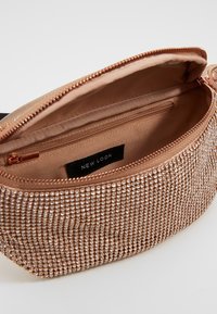 Borsa a tracolla in oro rosa con decorazioni simili a gemme, chiusura con zip e una fodera interna liscia con una tasca aggiuntiva.