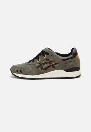 Sneaker in olijfgroen en zwart met oranje accenten, zwarte veters, witte zool en tekst "GEL LYTE III" aan de hielzijde.