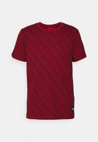 Camiseta roja con patrón de remolino negro; mangas cortas; cuello redondo; incluye una pequeña etiqueta con logo en la parte inferior derecha.