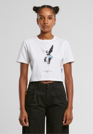 Hvid cropped t-shirt lavet af bomuld med korte ærmer, med et grafisk print af en vinget figur i sort og blå i midten.