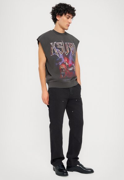 Gray sleeveless graphic sweatshirt featuring a bold "KSUBI" logo and colorful print. Paired with black trousers and black shoes.