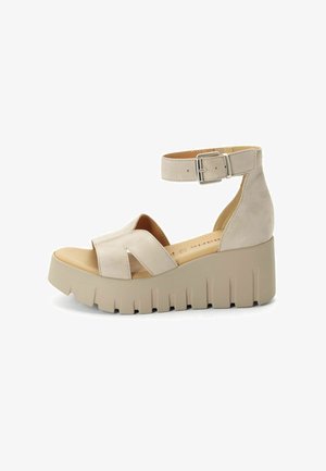 Sandali platform beige con cinturino alla caviglia, realizzati in materiale effetto suede, con design incrociato sulla tomaia e suola spessa e zigrinata.