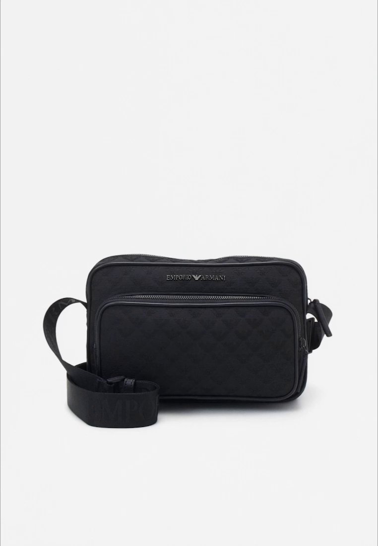 Sac bandoulière noir à texture matelassée, avec une poche zippée à l'avant et une sangle réglable embossée du nom de la marque.