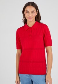Rode polo shirt met korte mouwen, voorzien van knoopsluiting en gestructureerde breipatronen. Beschikbaar in een relaxte pasvorm met een kraag.