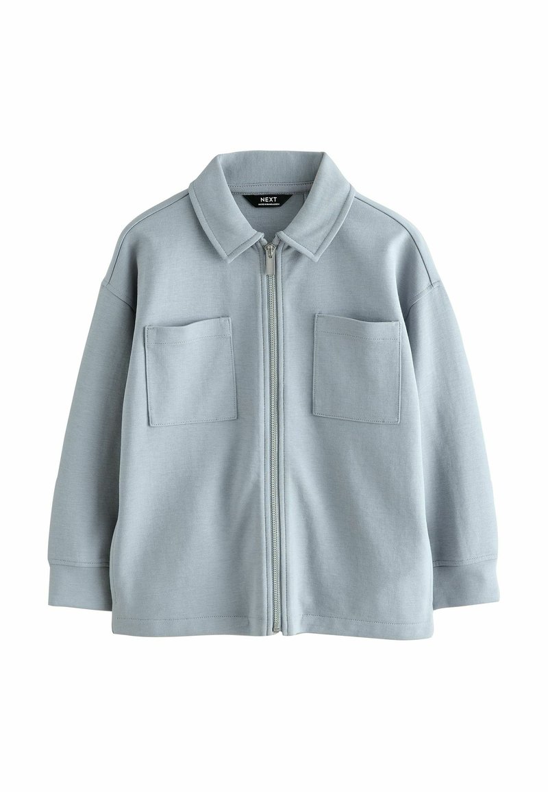 Chaqueta azul claro con cremallera, cuello, dos bolsillos en el pecho y un corte relajado. Fabricada con una tela suave y con una textura lisa.