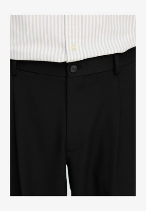 Black tailored trousers featuring a smooth texture, button closure, and belt loops, paired with a striped light shirt.