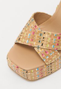 Woven straw wedge sandal with multicolored accents. Features a tan synthetic footbed and a cross-band design for support.