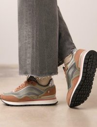 Zapatillas deportivas con una mezcla de ante marrón y tela verde, con detalles en plata, una entresuela blanca y una suela exterior de goma negra texturizada.