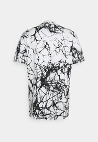 T-shirt à manches courtes avec un motif craquelé en noir et blanc. Fabriqué en tissu léger, doté d'un col rond et d'une coupe décontractée.
