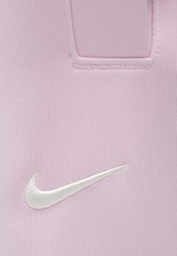 Το αθλητικό ύφασμα σε ανοιχτό ροζ χρώμα έχει λευκό κεντημένο λογότυπο Nike. Η υφή είναι λεία με εφαρμοστή και άνετη γραμμή και ελάχιστα ραφές.