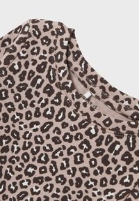 Tijgerprint top met een ronde hals, gemaakt van zachte stof; heeft donkerbruine en witte vlekken op een licht beige achtergrond.