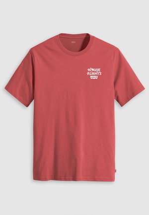 T-shirt in cotone rosso con maniche corte e collo tondo, con testo bianco che dice "HOUSE PLANT'S" sopra un logo Levi's sul lato sinistro del petto.