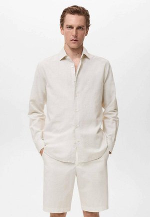 Cămașă din in bej deschis, cu guler tip button-down, mâneci lungi și croială lejeră, asortată cu pantaloni scurți corespunzători. Textură netedă, design minimalist.