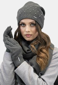 Gray knitted beanie with diamond pattern and embellishments, accompanied by matching gloves and a scarf, all featuring a soft texture.