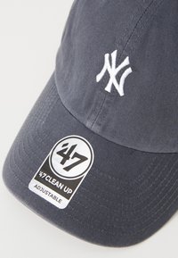 Navy verstelbare baseballcap met een wit geborduurd New York Yankees-logo en een zwart label met de tekst "47 CLEAN UP."