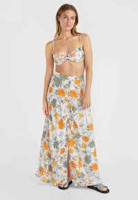 Top de bikini fleuri avec bretelles réglables et un devant noué, associé à une longue jupe fluide à motifs orange et verts.