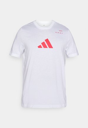 Camiseta blanca de algodón con un logo rojo de Adidas en el centro y texto "PADDEL 15_30_40_A" en la parte superior izquierda. Mangas cortas y cuello redondo.