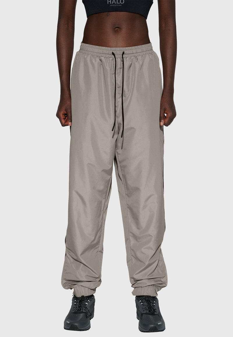 Lätta, beige, vattentäta joggerbyxor med elastiska muddar och linning; dragsko i midjan; används med svarta, robusta skor.