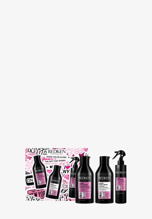 Le set-cadeau Redken Acidic Color Gloss comprend quatre bouteilles noires avec des étiquettes roses, présentées dans un coffret au design graphique vibrant.
