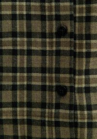 Tessuto a quadri marrone e nero con una trama texturizzata, caratterizzato da grandi quadrati e un accento di bottone nero. Adatto per una camicia con bottoni.