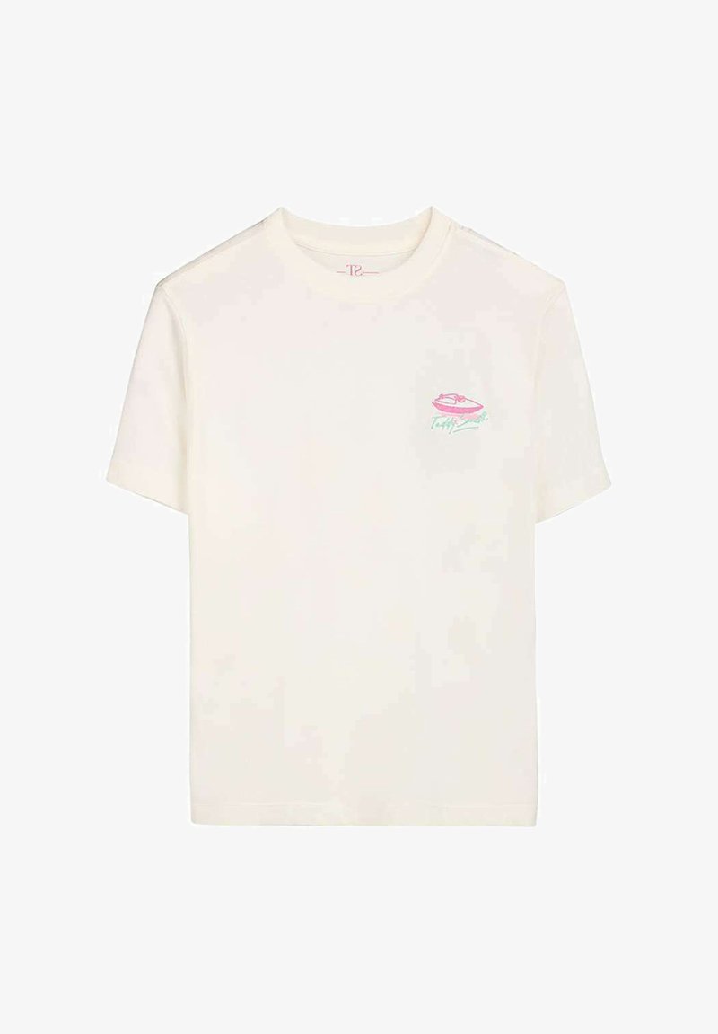 T-shirt blanc à manches courtes avec un petit motif de lèvres roses et un texte turquoise sur la poitrine à gauche.