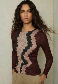 Maglietta a maniche lunghe in bordeaux, nero e rosa pallido con motivo a zigzag; tessuto texturizzato con dettagli arricciati in vita.