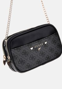 Borsa a tracolla nera e grigia in tessuto con motivo floreale, hardware dorato, tracolla a catena e chiusure con zip. Presenta un logo sul davanti.