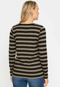 Långärmad topp med horisontella svarta och beige ränder, tillverkad av mjukt tyg, med rund halsringning och avslappnad passform.