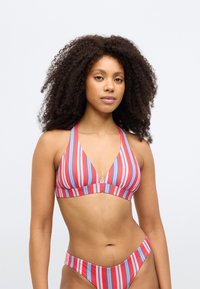 Svītrainu bikini komplekts sarkanā, zilā un baltā krāsā. Raksturo trīsstūrveida augšu ar dziļu izgriezumu un augsti izgrieztiem apakšdaļas biksītēm. Gluda auduma tekstūra.