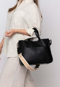 Borsa a mano nera in pelle con superficie testurizzata, doppio manico e tracolla staccabile con un accento beige. Design semplice e strutturato.