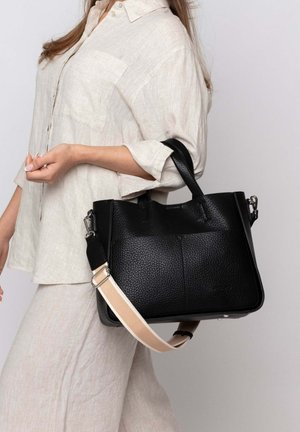 Schwarze Lederhandtasche mit strukturierten Oberflächen, doppelten Griffen und einem abnehmbaren Gürtel mit beigem Akzent. Schlichtes, strukturiertes Design.