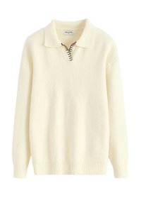 Pull-over couleur crème avec col, demi-fermeture éclair et ourlet côtelé. Confectionné en matière douce avec des détails de coutures apparentes.