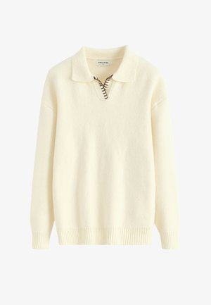 Pull-over couleur crème avec col, demi-fermeture éclair et ourlet côtelé. Confectionné en matière douce avec des détails de coutures apparentes.