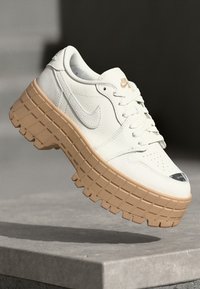 Hvide lædersneakers med forhøjet platformssål i lys tan. Har rund tå, snørebånd og lille logo på siden og på tungen.