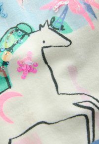 Cotton fabric with a pastel background features a black outlined unicorn and colorful sequins in pink and blue accents.