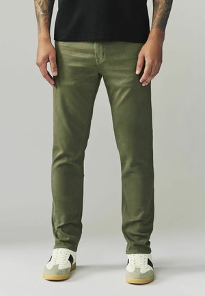 Groene katoenen broek met een slim fit, met een soepele textuur. Gecombineerd met witte sneakers en een zwart t-shirt.