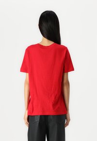 Red cotton t-shirt with a crew neckline, short sleeves, relaxed fit, and a smooth texture. No visible patterns or hardware details.