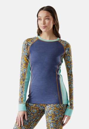 Langsleeve top in marineblauw met bloemenpatroon mouwen in blauw en geel. Heeft een lichtblauwe kraag en contrasterende naden.