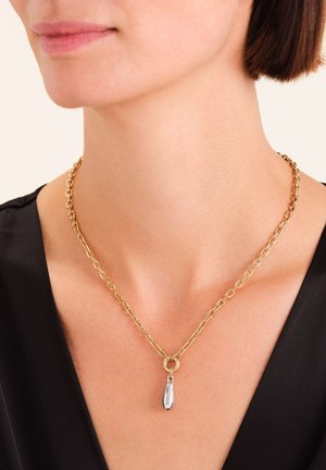 Zlatna ogrlica s ovalnim karikama, s tekućim privjeskom u obliku suze koji visi s okruglog spojnika.