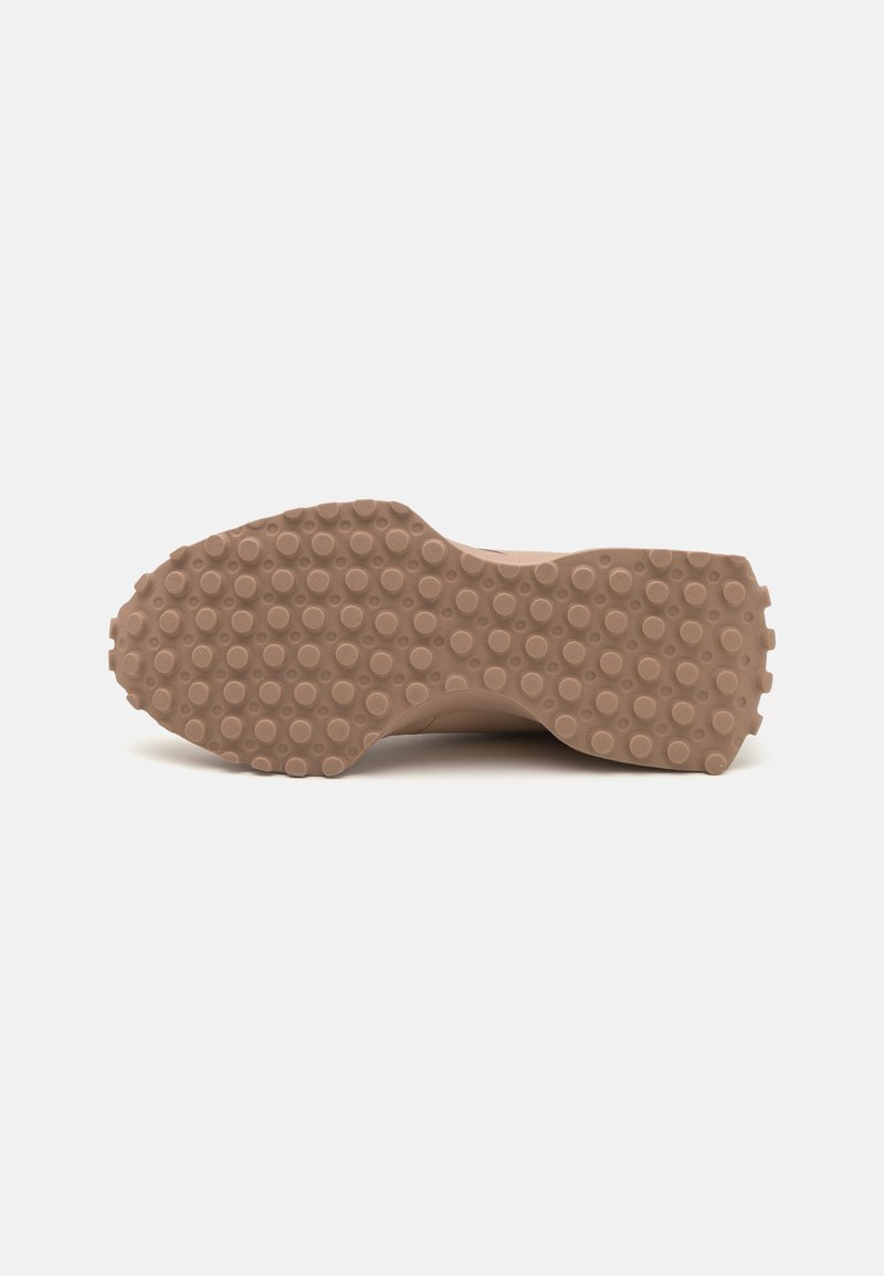 Semelle de chaussure en caoutchouc marron clair avec des grips ronds texturés, des bords lisses et une forme courbée, conçue pour l'adhérence et le confort.