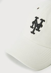 Valge kummitrossiga beisballi müts, millel on must broderitud logo. Omab kõverat ääret ja tekstuuri, mis on kooskõlas kummitrossi kangaga.