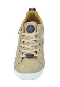 Zapatilla de lona beige con puntera redonda, parte superior texturizada, cordones en contraste, parche con logo y detalle de cremallera en el lateral. Suela de goma blanca.