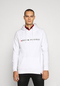 Baltas džemperis su priekine kišene ir raišteliu ant gobtovo, ant kurio užrašyta „DENIM PROJECT“ juoda spalva. Textūruotas audinys ir laisvas siluetas.