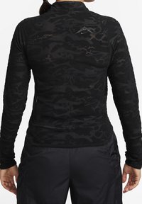 Černý dlouhý rukáv sportovní top s texturovanou, vzorovanou tkaninou. Má vysoký límec a malé logo Nike na zadní straně.