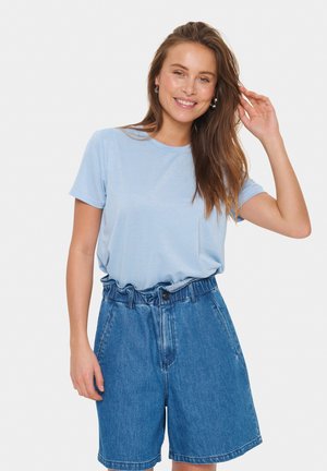 T-shirt bleu clair à manches courtes, associé à un short en denim taille haute avec un waistband froncé et une fermeture à bouton.