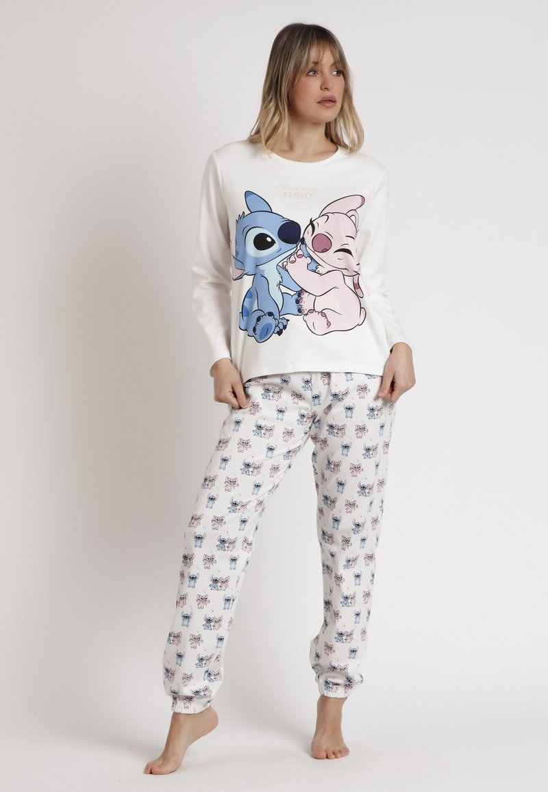 Top blanco de manga larga con un gráfico de un personaje de dibujos animados en azul y rosa. Pantalones blancos a juego con un patrón repetido del personaje de dibujos animados.
