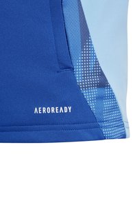 Blauwe sportshirt met een soepele textuur, kleurverloop met subtiele patronen en het "AEROREADY" logo in het wit aan de zijkant.
