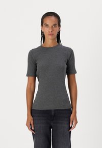T-shirt grigia attillata a maniche corte realizzata in un mix di cotone texture. Collo liscio, design minimale, abbinato a jeans scuri a gamba dritta.