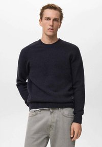 Mornarica pletena pulover s okruglim izrezom, dugim rukavima i rebrastim manžetama i rubom. Izrađen od mekog materijala, s glatkom teksturom.